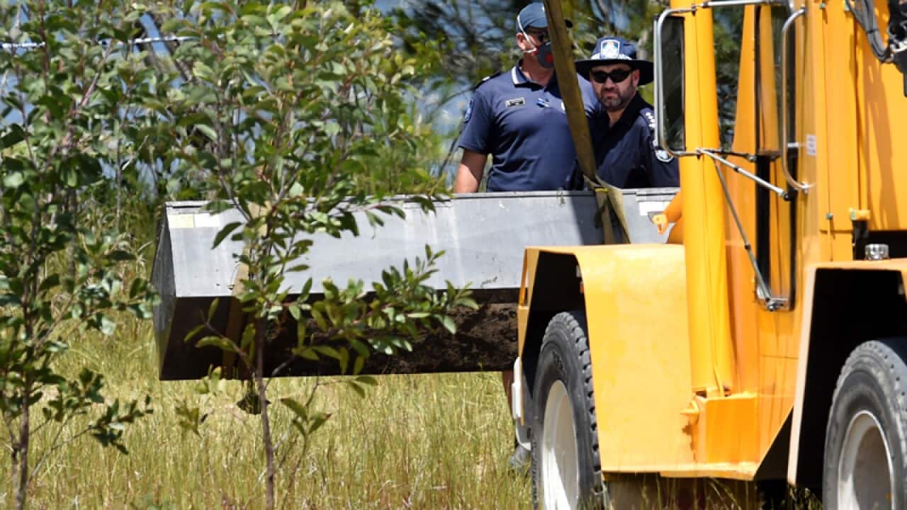 Police uses a crane to retrieve a metal box from a dam