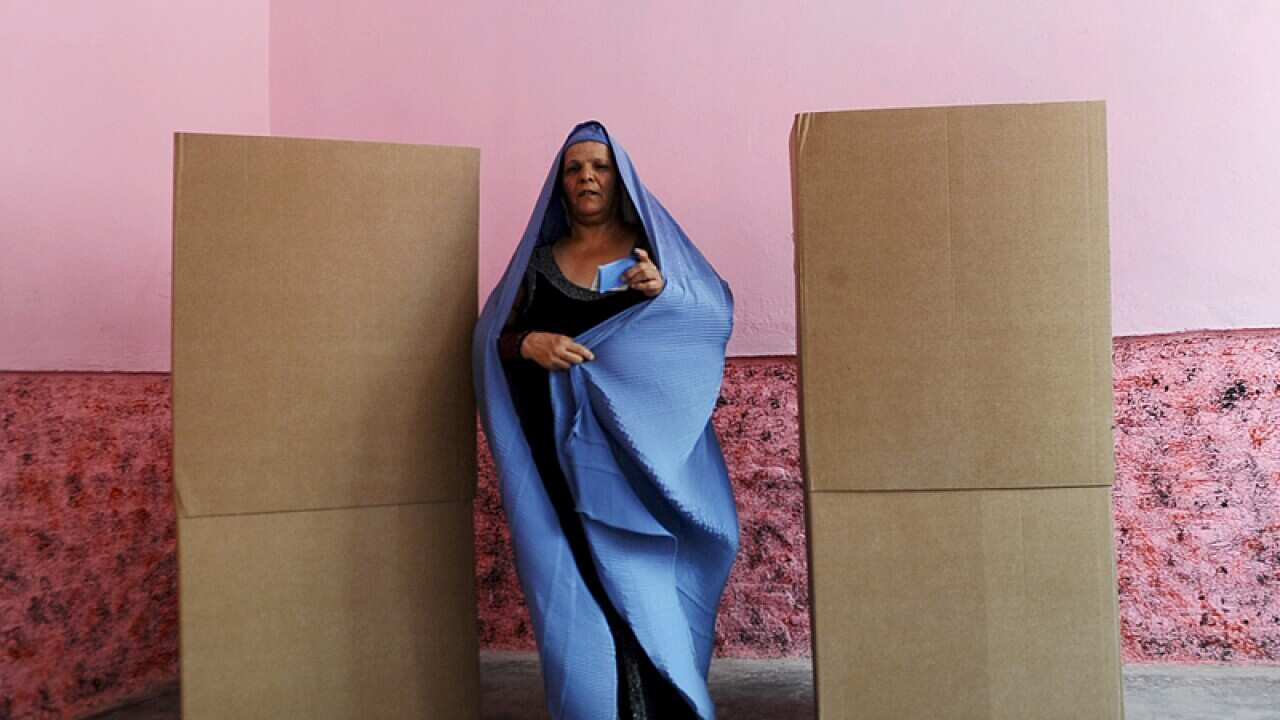 An Afghan voter walks after casting her ballot