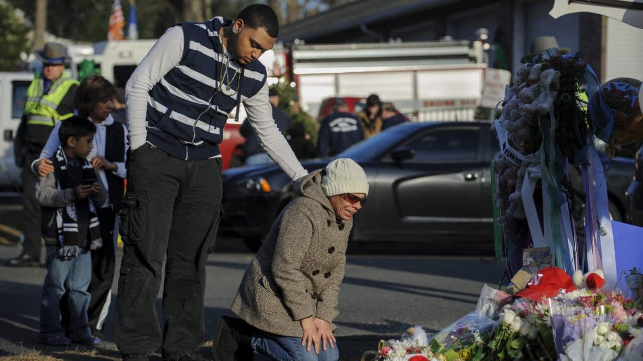 Loved ones visit a memorial for the victims of the Sandy Hook Elementary school a day after the shooting.