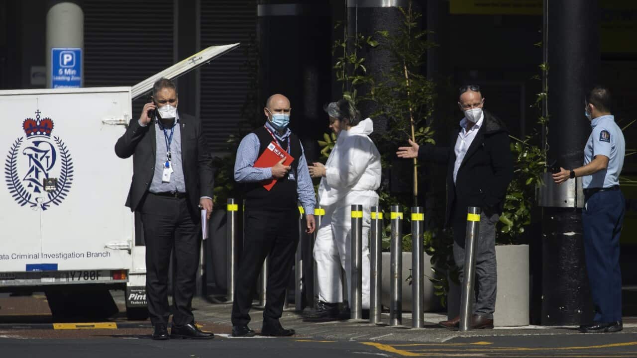 Police and forensic staff stand outside the Auckland supermarket that was the site of a stabbing attack.