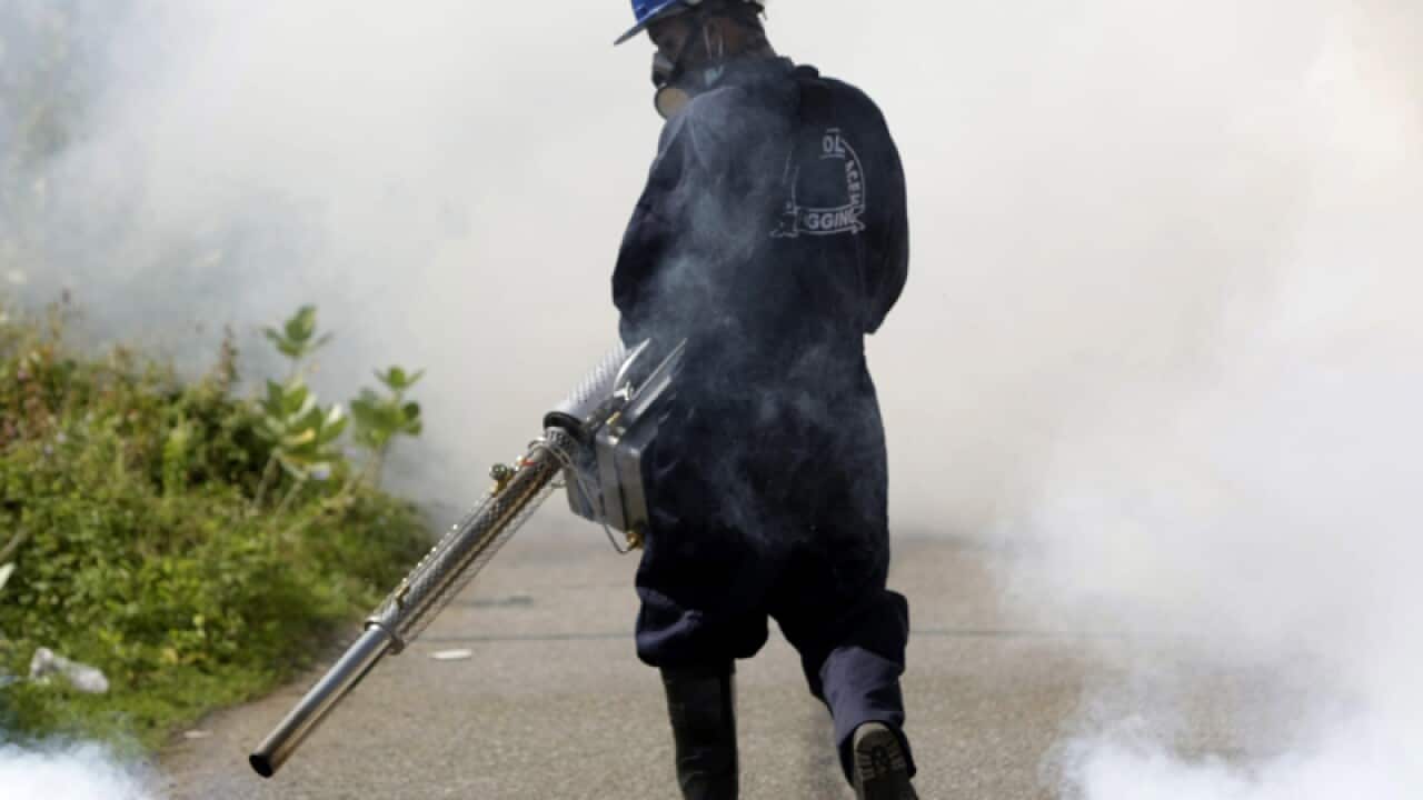 An Indonesian health worker sprays pesticide