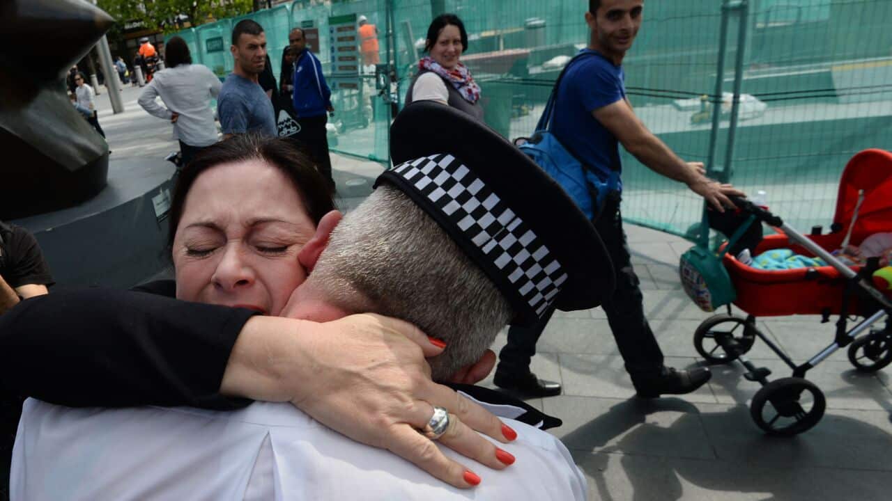 Gill Hicks embraces a uniformed officer on a London street.