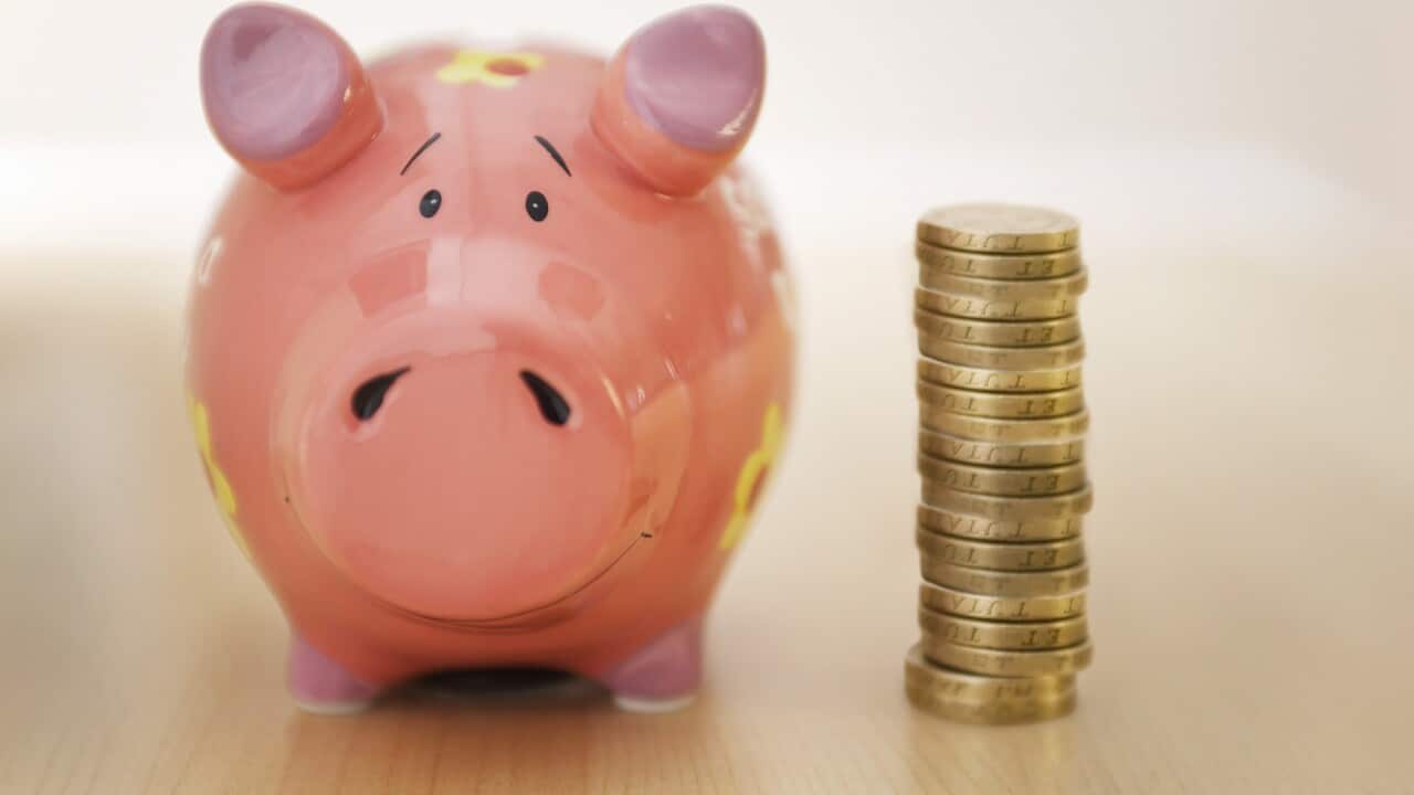 A piggy bank is placed next to a pile of coins.