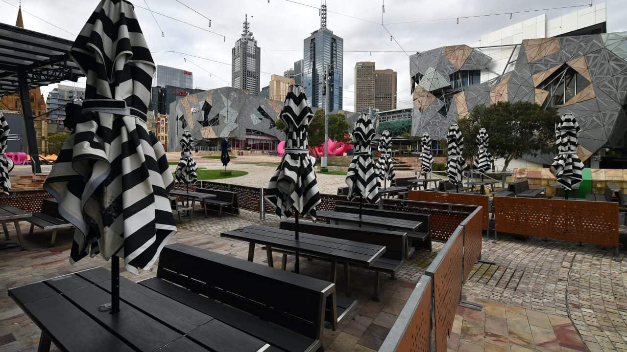 Empty tables are seen at a closed restaurant in Federation Square, Melbourne.