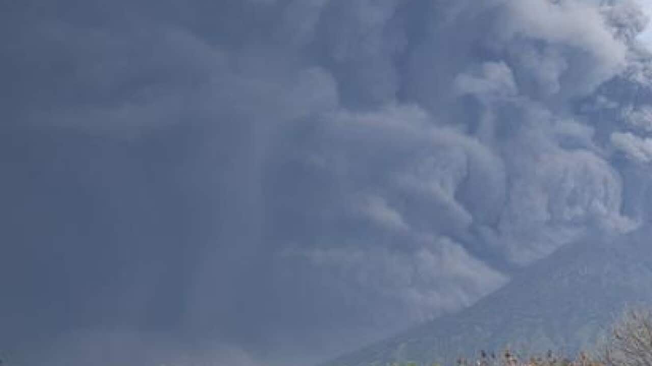 A farmer works on his farm as Mount Agung volcano spews volcanic ash.