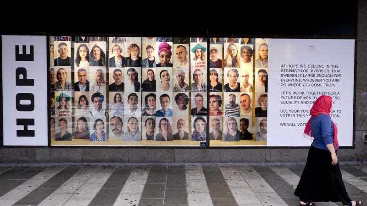In this Aug. 31, 2018 photo a woman walks by an advertising for diversity and tolerance in the window of shopping mall in Stockholm, Sweden.