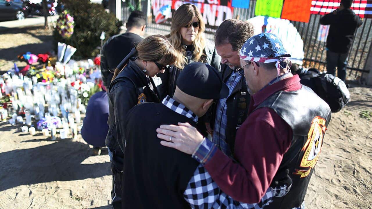 People pray together as they pay their respects at a memorial near the Inland Regional Center