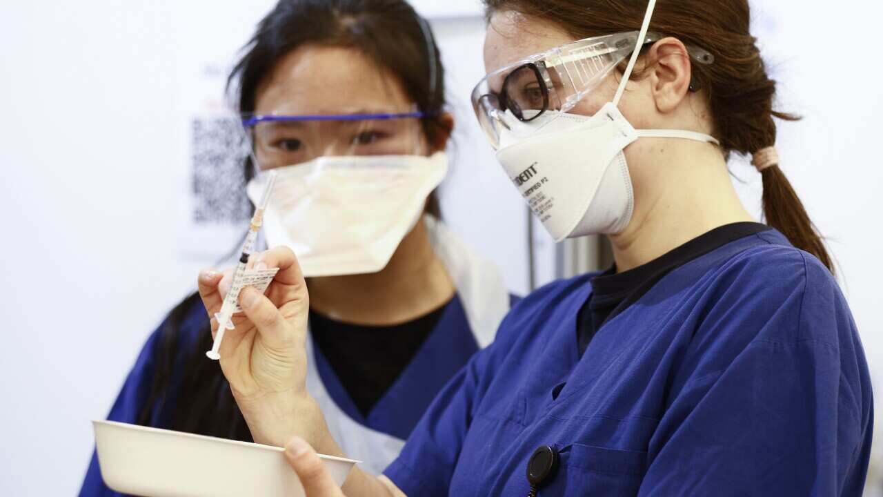 Health workers inspect a Pfizer vaccination syringe in Melbourne.