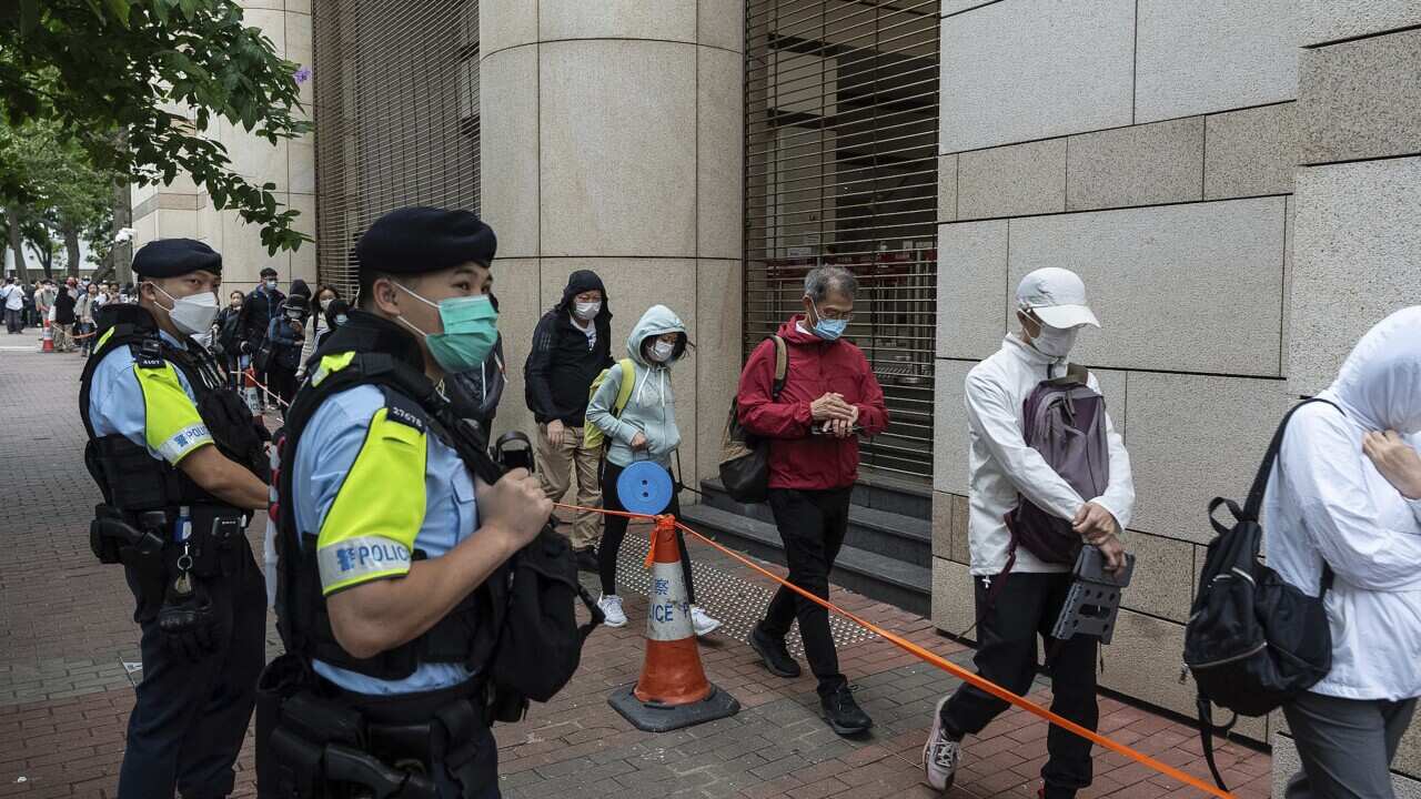 Police watch as activists walk into the West Kowloon Magistrates' Courts in Hong Kong