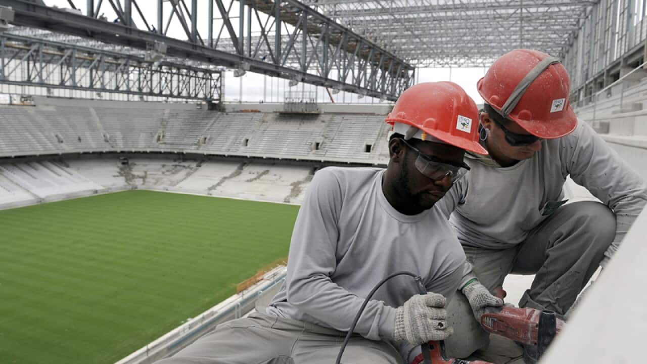 Workers build the Itaquerao World Cup stadium