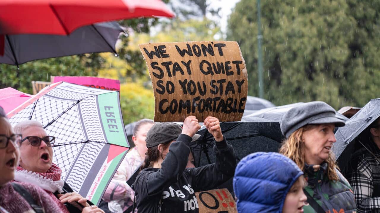 A protester holds a placard that says " We wont stay quiet