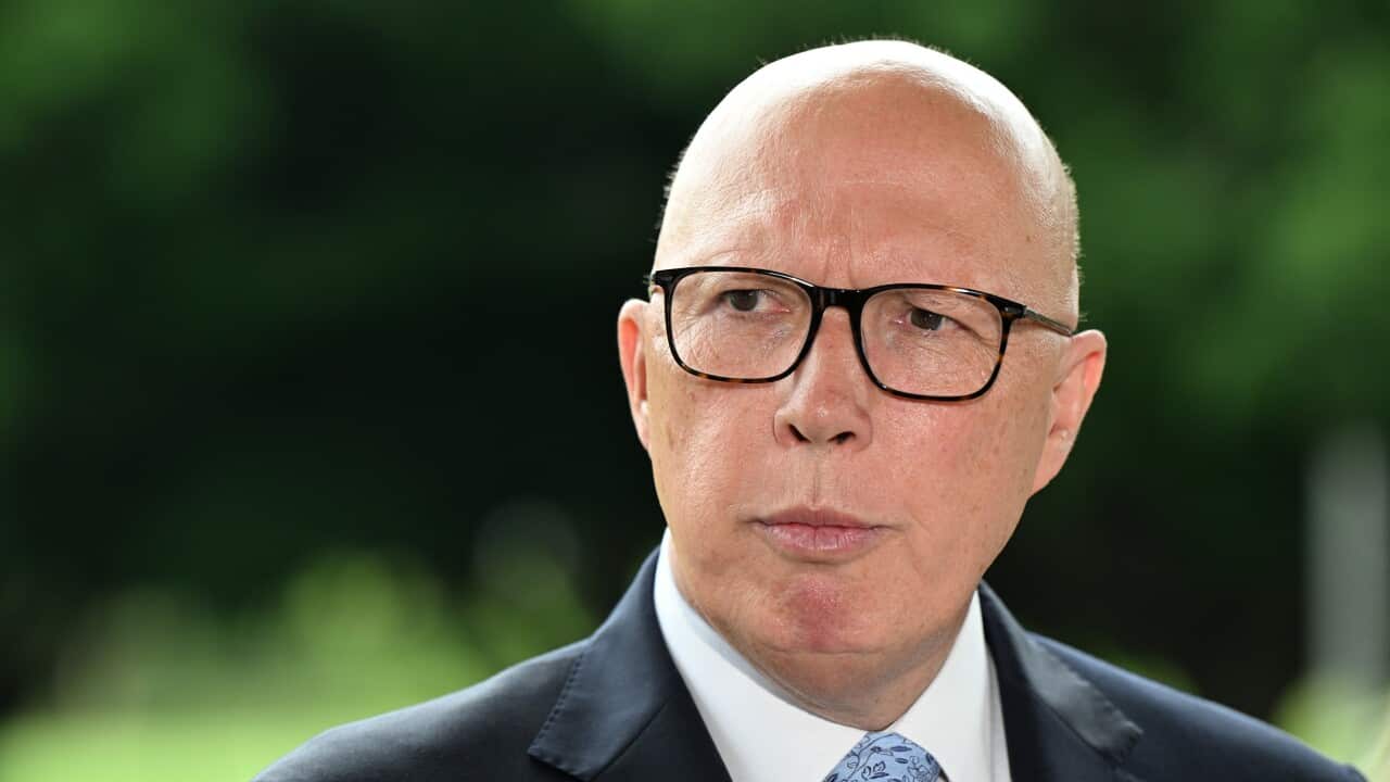 Peter Dutton in a suit, in front of a blurred background of trees.