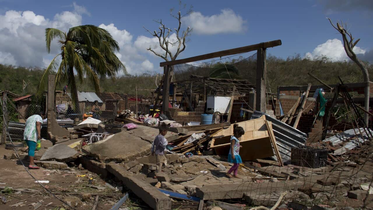Residents walk through the debris of homes destroyed by Hurricane Patricia, in Chamela