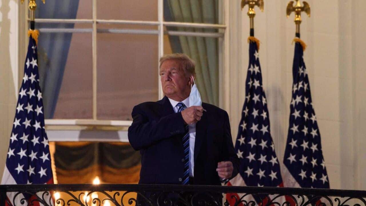 US President Donald Trump takes off his mask as he arrives at the White House upon his return from Walter Reed Medical Center