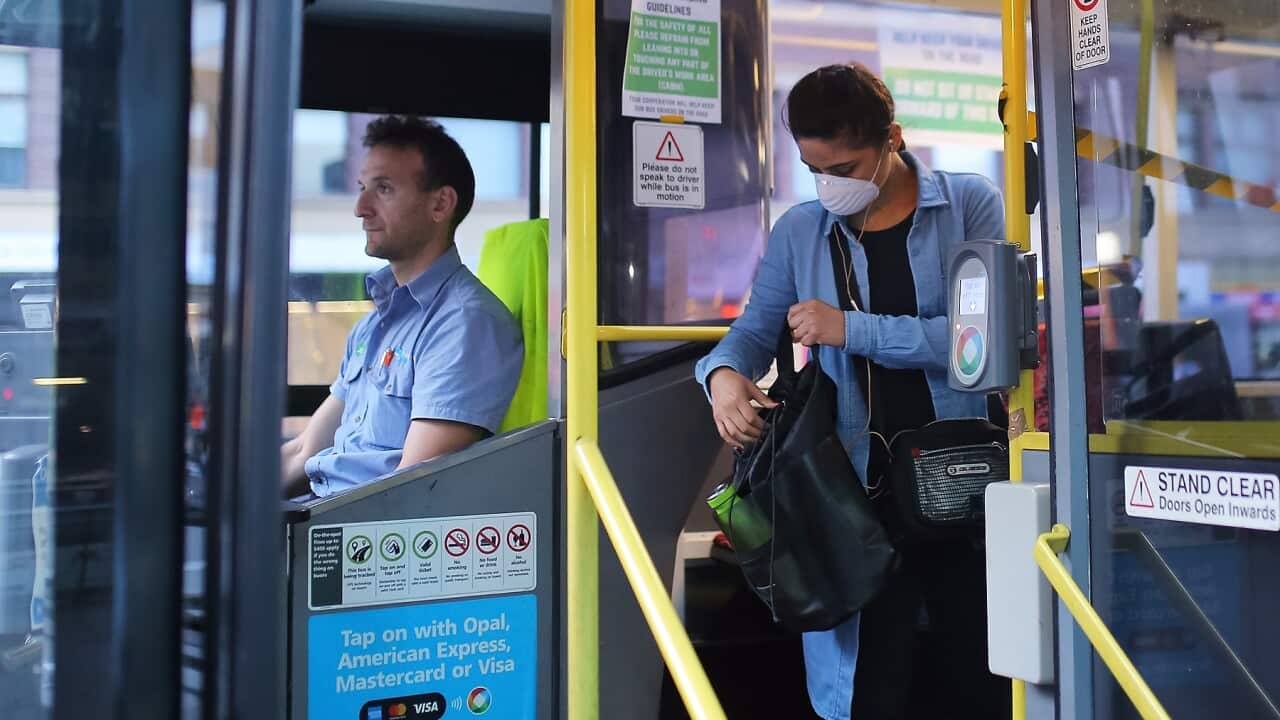 A woman wearing a mask against COVID-19 boards a Sydney bus