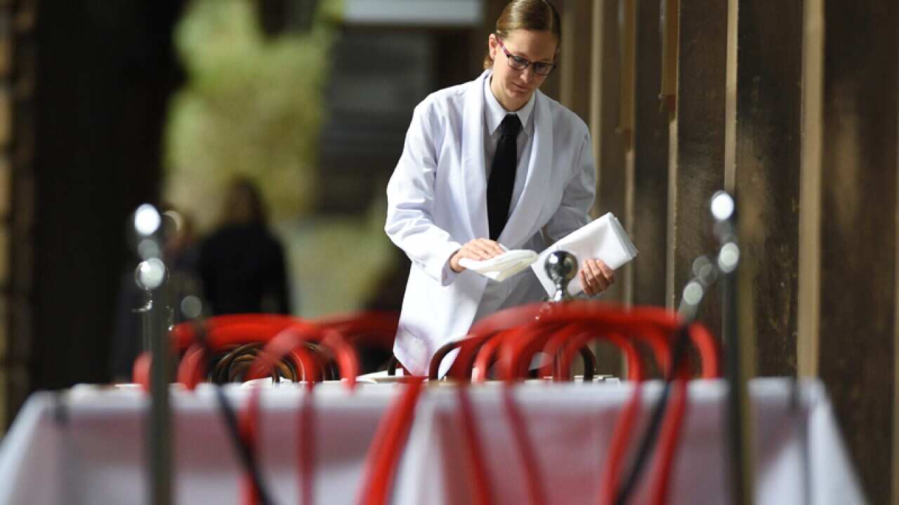 A waitress sets a table at a restaurant in Sydney