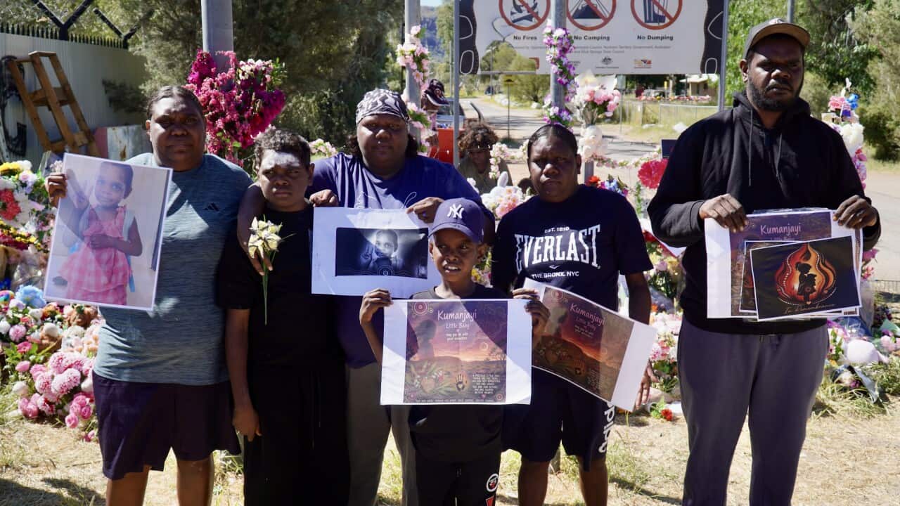 Members of Kumanjayi Little Baby's family hold up photos and tributes to her