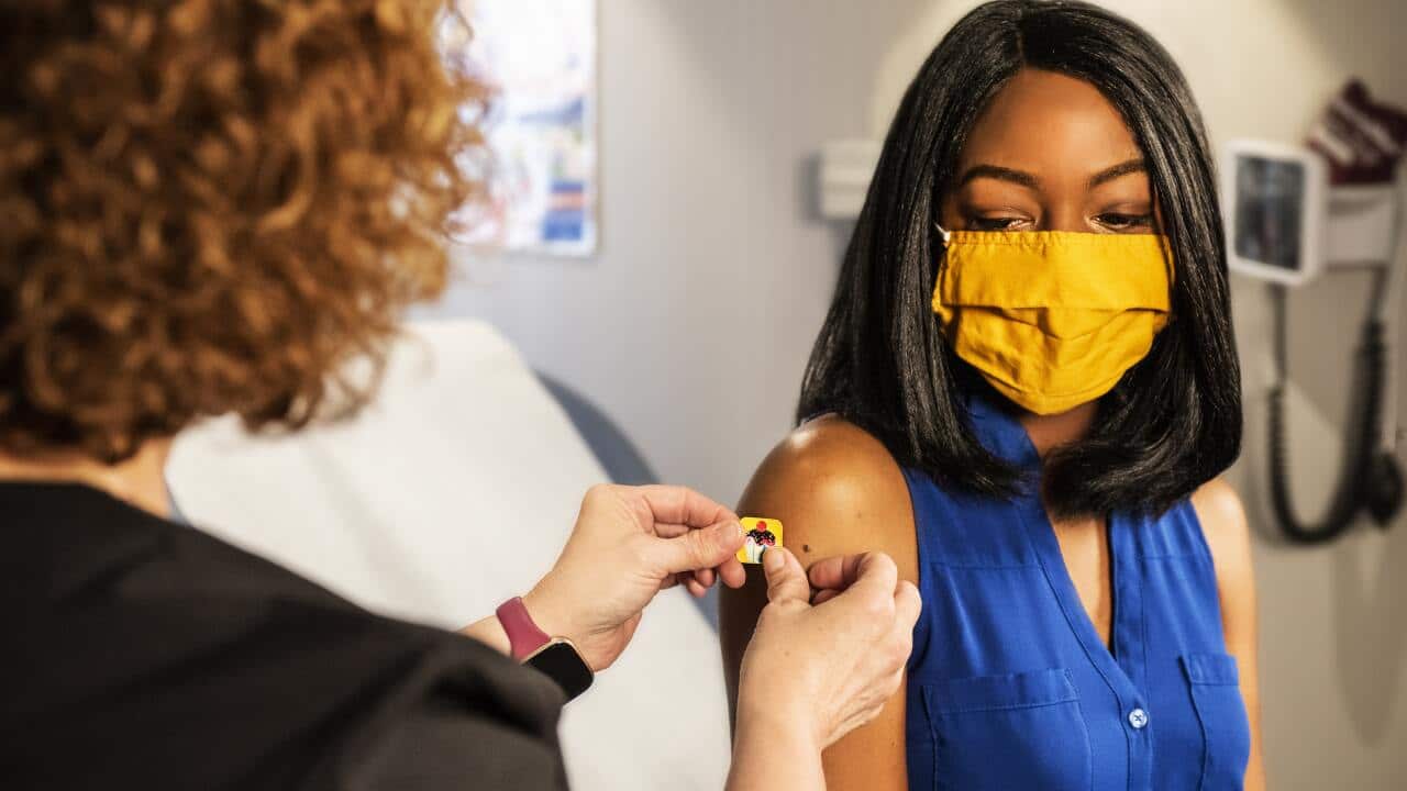 In this 2020 photograph, captured inside a clinical setting, a health care provider and patient, consult on influenza vaccine options.