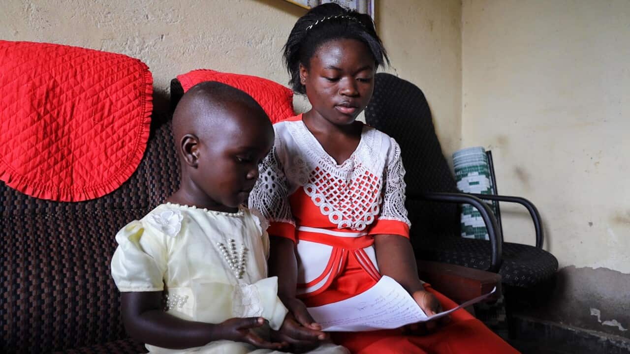 Ghislene and her sister Yuha with a letter they wrote to Australia's Prime Minister, asking to help children who have lost their parents to Ebola