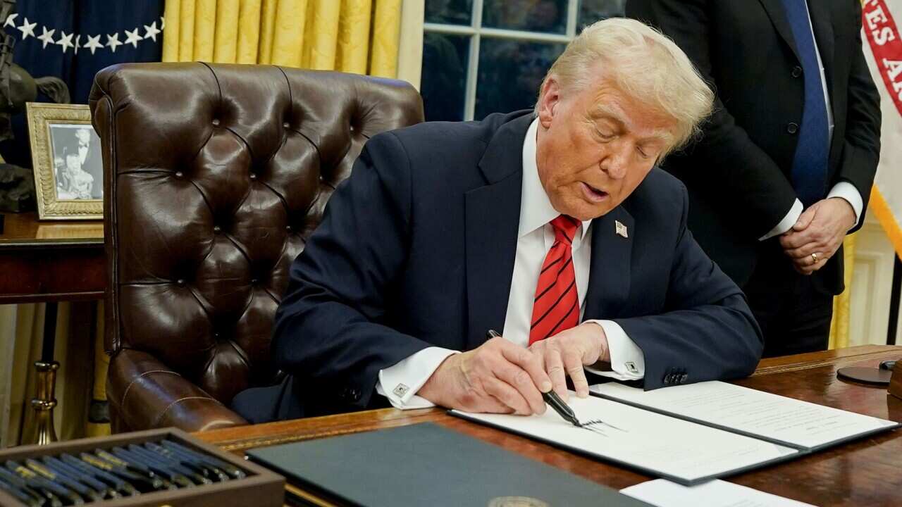 Il Presidente americano Donald Trump mentre firma decreti attuativi nello Studio Ovale della Casa Bianca.
