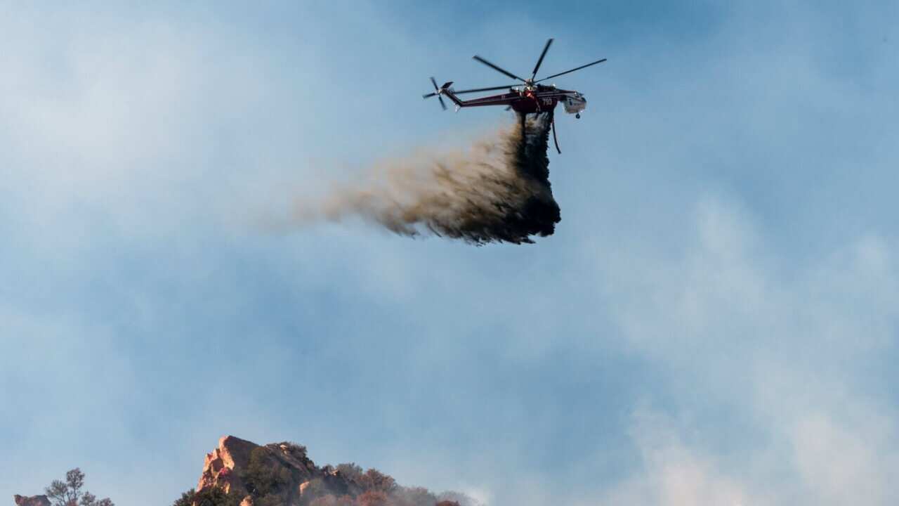 A helicopter makes a water drop on the Woolsey Fire near Malibu, California