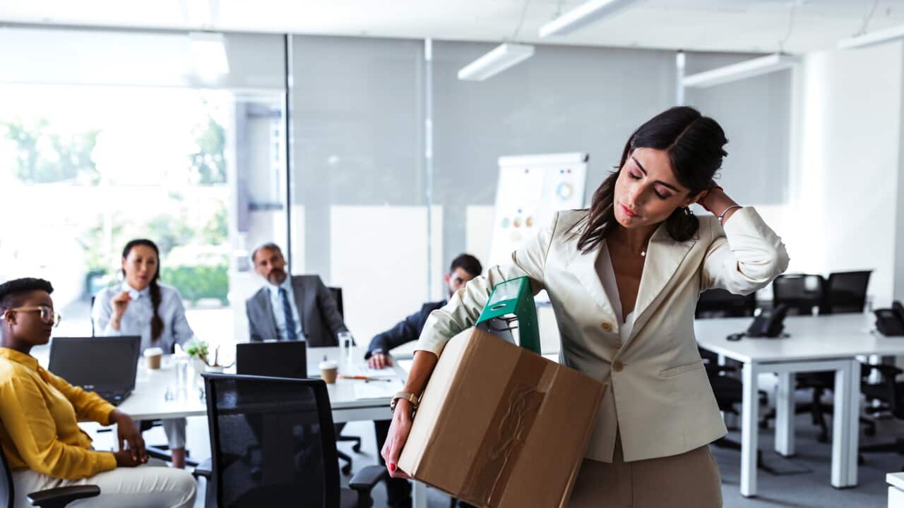 Mid adult businesswoman with cardboard box being fired