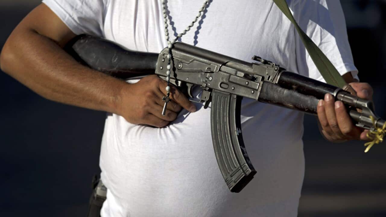 A man belonging to a self-defence group holds an AK-47
