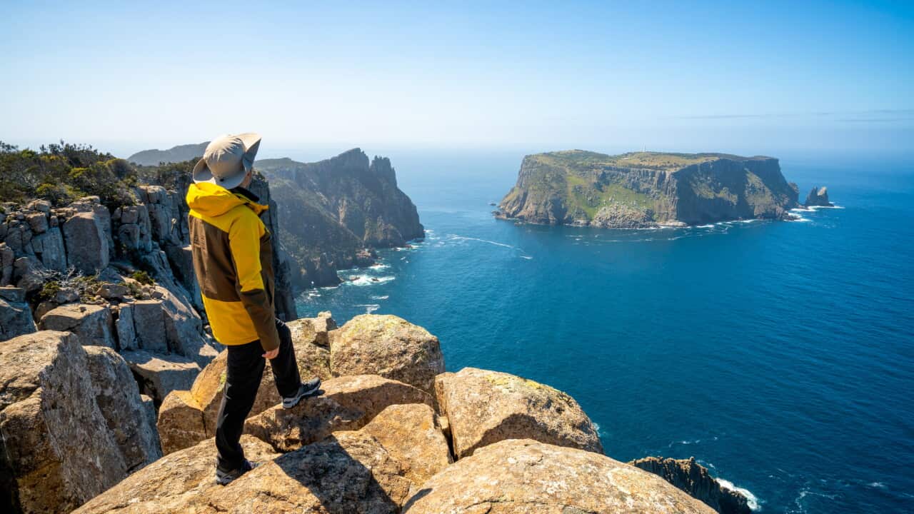 Young man trekker hiking on beautiful coast cliff of Tasman National Park in Tasman peninsula, Three Capes Track near Port Arthur in Tasmania, Australia.