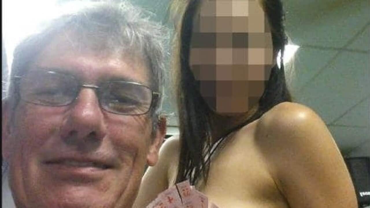 Ross Macdonald posing with a topless woman in Thailand. 