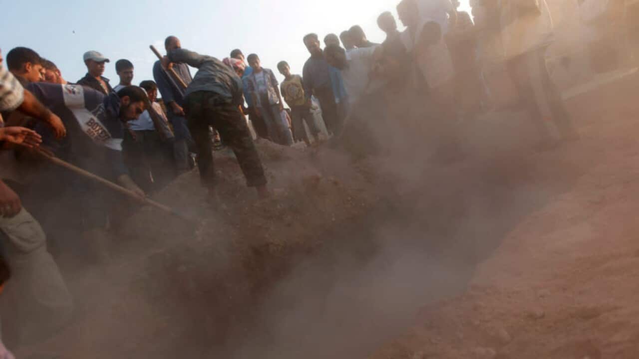 In this file photo, Syrians throw the earth over the grave of 29 year-old Free Syrian Army fighter, Husain Al-Ali, who was killed during clashes in Aleppo.