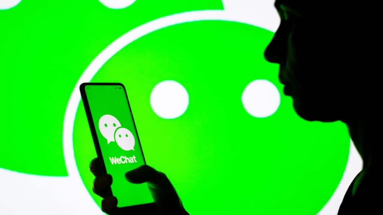 A woman holds a photo with the WeChat logo.