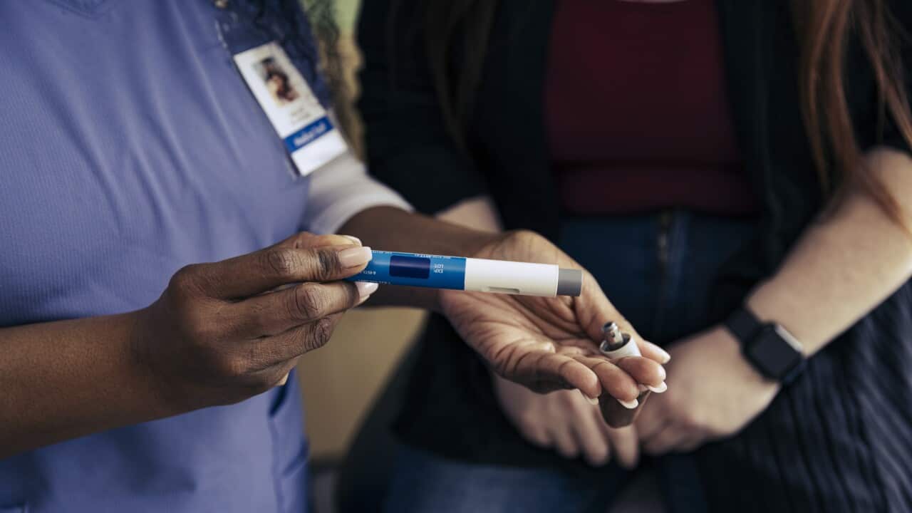 Hand of female nurse holding weight loss injection pen in exam room at doctor's office