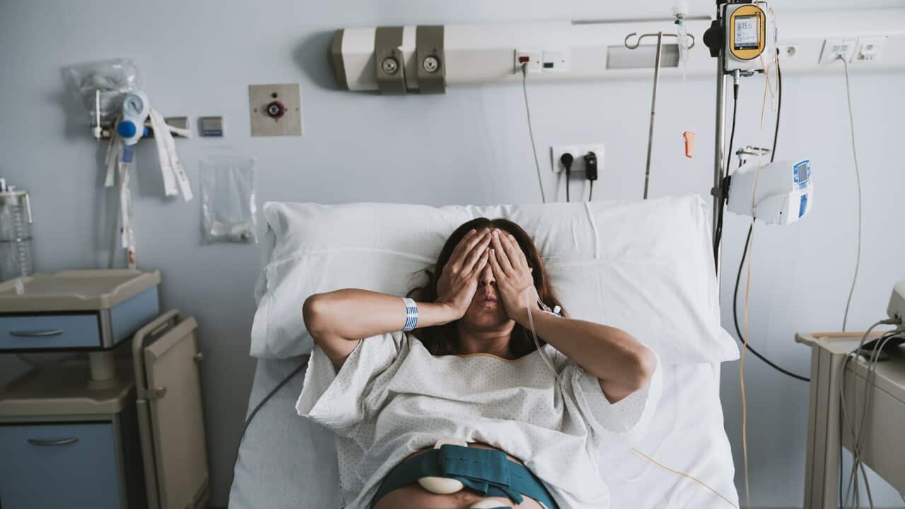 Stressed pregnant woman lying on bed in hospital