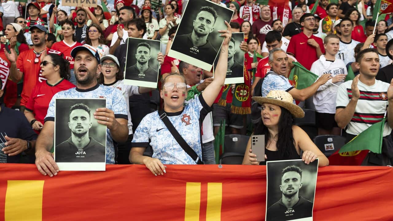 Football fans hold up photos of Diogo Jota.