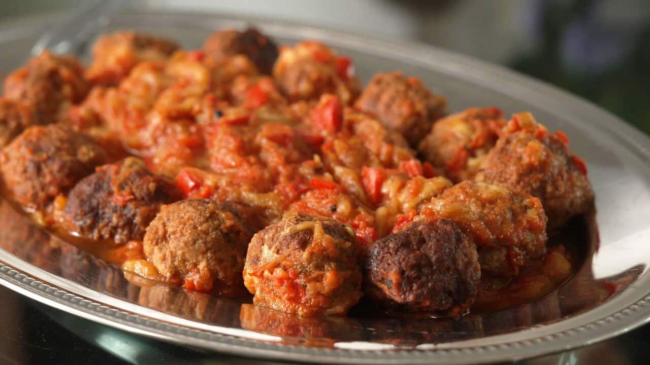An oval silver tray holds a thick tomato-y stew surrounded by a ring of meatballs.