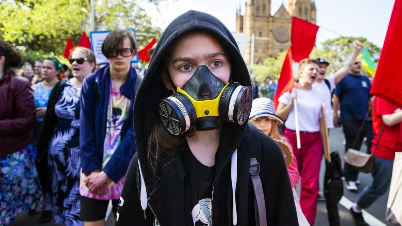 A girl wearing a gas mask marches along College Street during a climate strike rally on 20 September, 2019 in Sydney.