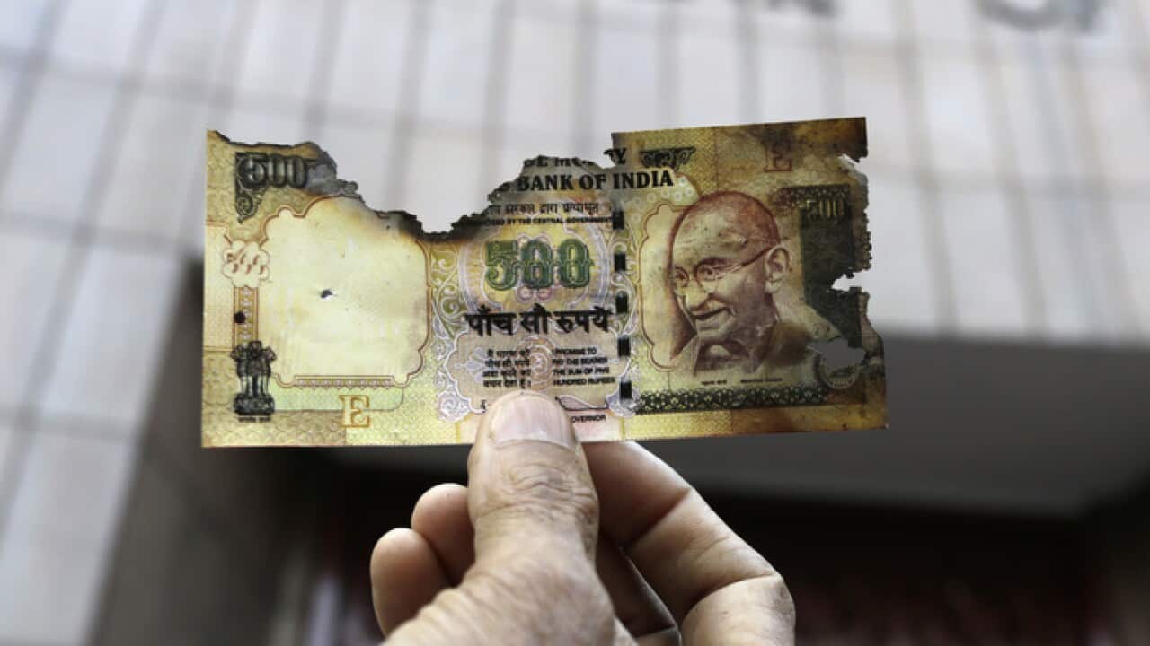 A man holds a charred facsimile of Indian currency 500 note outside Reserve Bank of India in Kolkata, as traders demand better exchange facilities