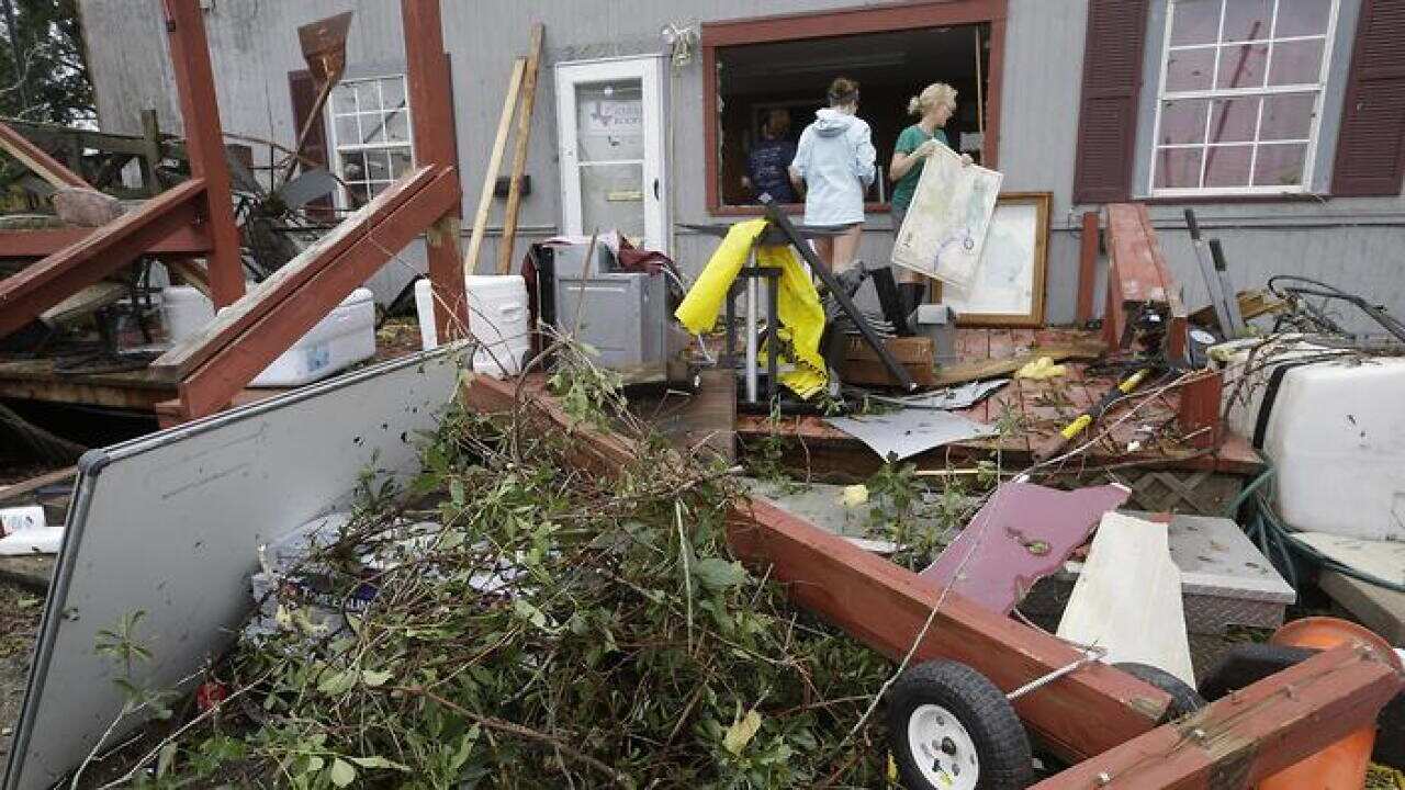 People collect debris from a building on the property of Bryant's Auto Sales in Katy, Texas, after a possible tornado during Hurricane Harvey on Saturday, Aug. 26, 2017. ( Melissa Phillip /Houston Chronicle via AP)