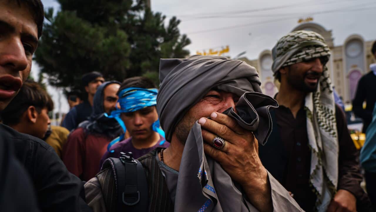 A man cries as he watches Taliban fighters conduct crowd control over thousands of Afghans who continue to wait outside the Kabul Airport.