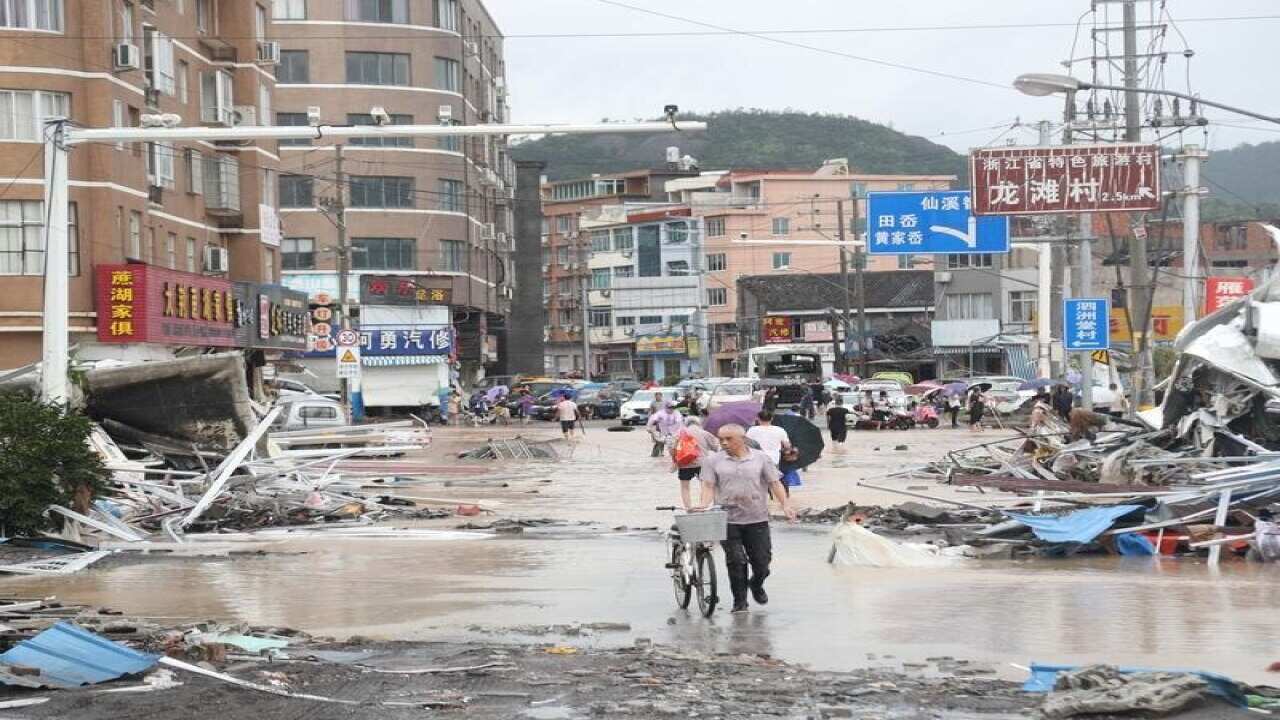 Residents walk on a flooded road after Typhoon Lekima