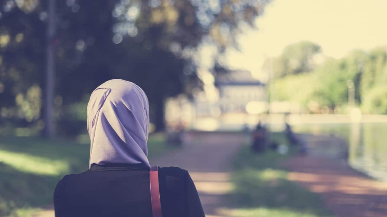Rear view of a veiled muslim woman walking in forest