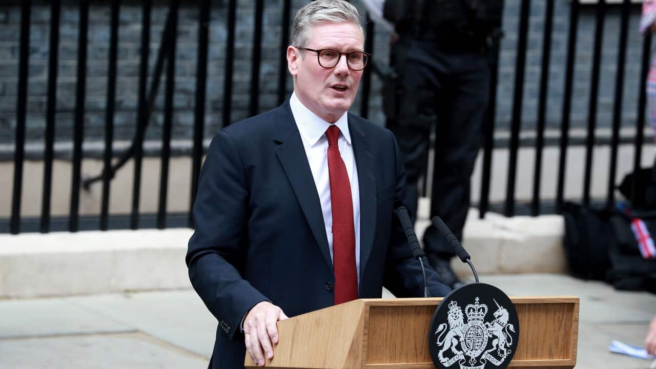 A man in a navy blue suit white shirt and red tie