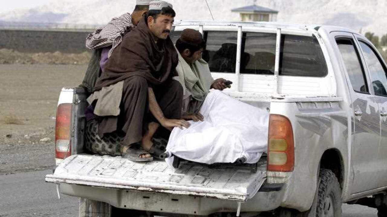 Afghan men move the dead body of a man after clashes between Taliban fighters and Afghan forces in Kandahar Airfield, Afghanistan, Wednesday, Dec. 9, 2015.