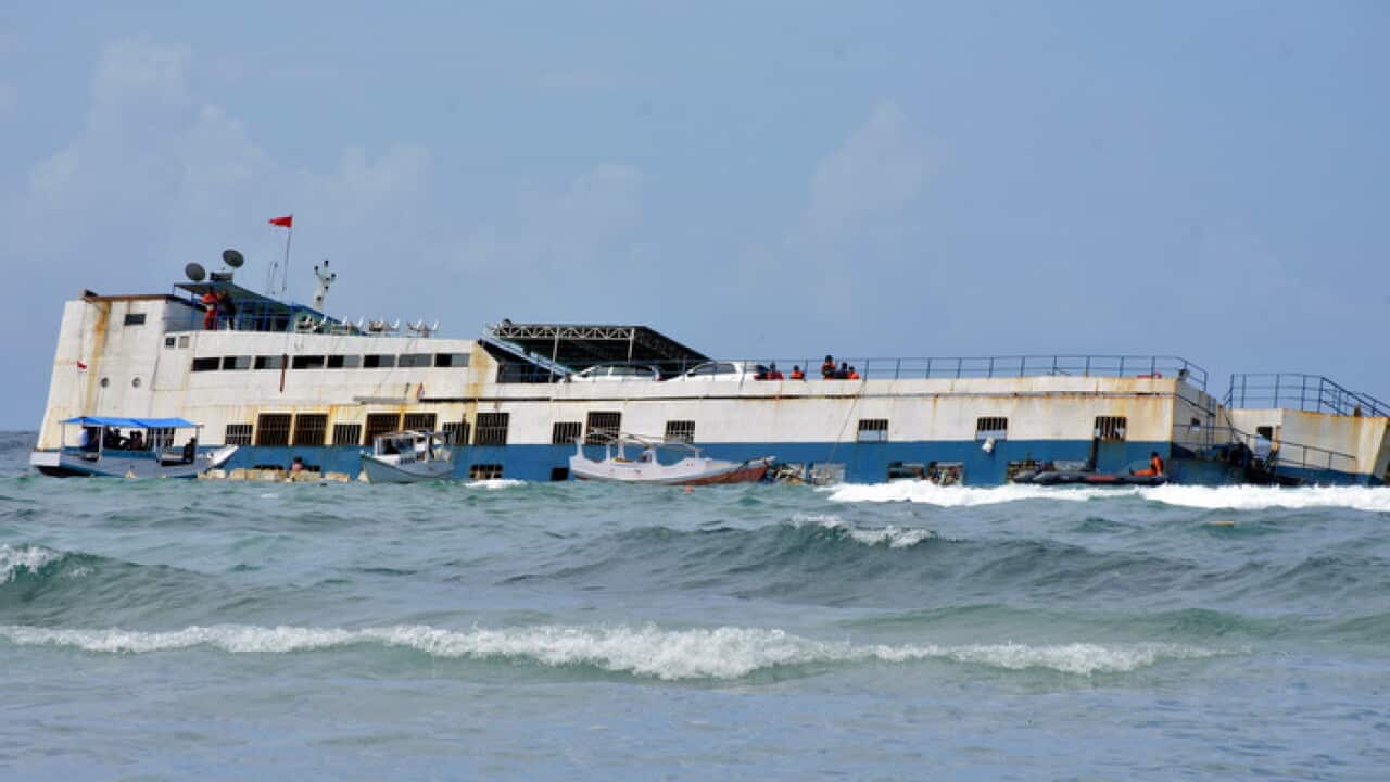 Rescuers stand on a passenger ferry ran aground on Tuesday off Selayar Island, Indonesia, Wednesday, July 4, 2018.