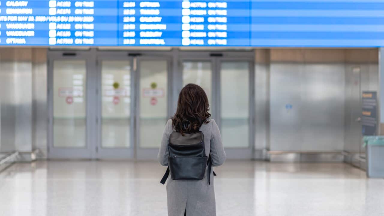 Shot of the back of a woman looking at the departure board