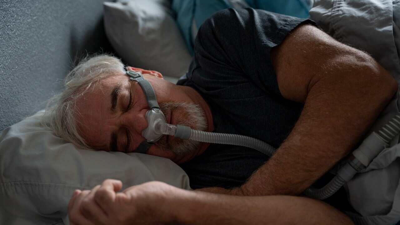 Mature Man With Sleep Apnea Wearing A CPAP Mask In Bed Sleeping