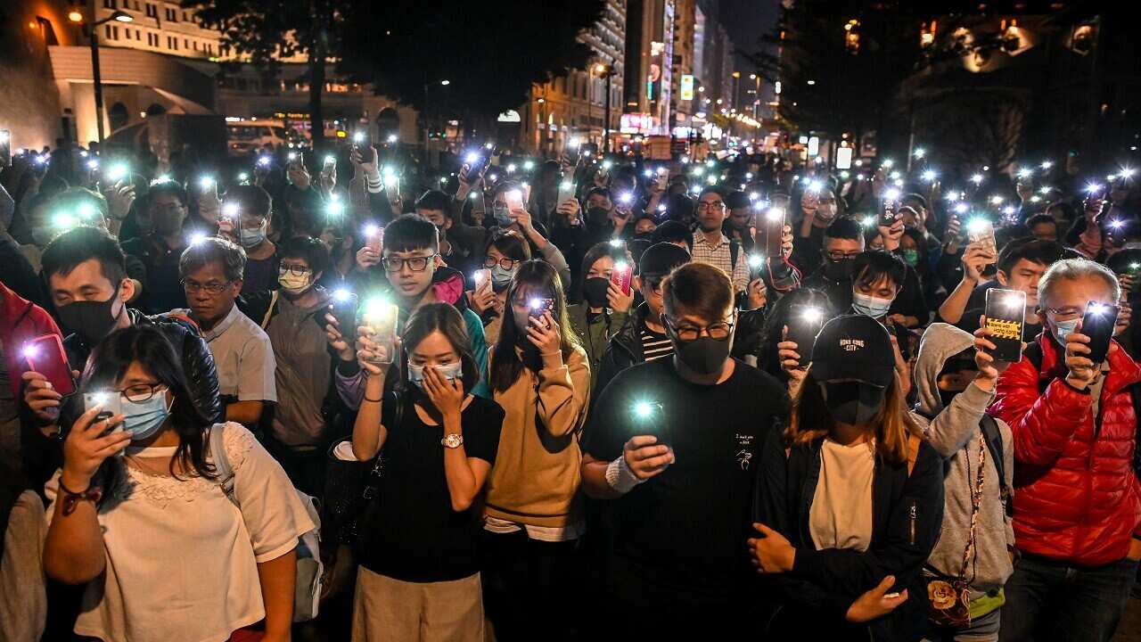 People hold their mobile phones as they gather to pray for the students who are barricaded inside Hong Kong Polytechnic University.