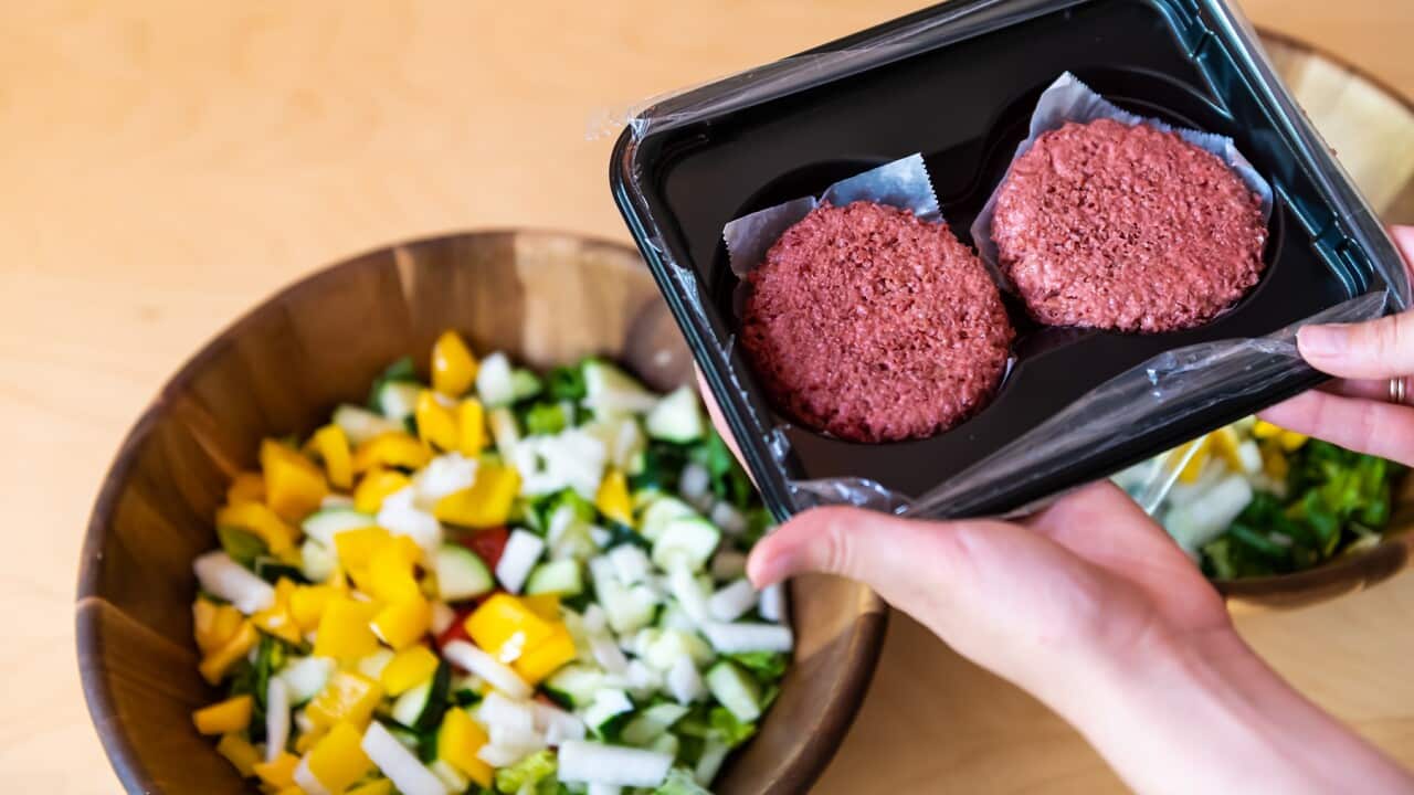 Two red vegan burgers in their packaging with salad