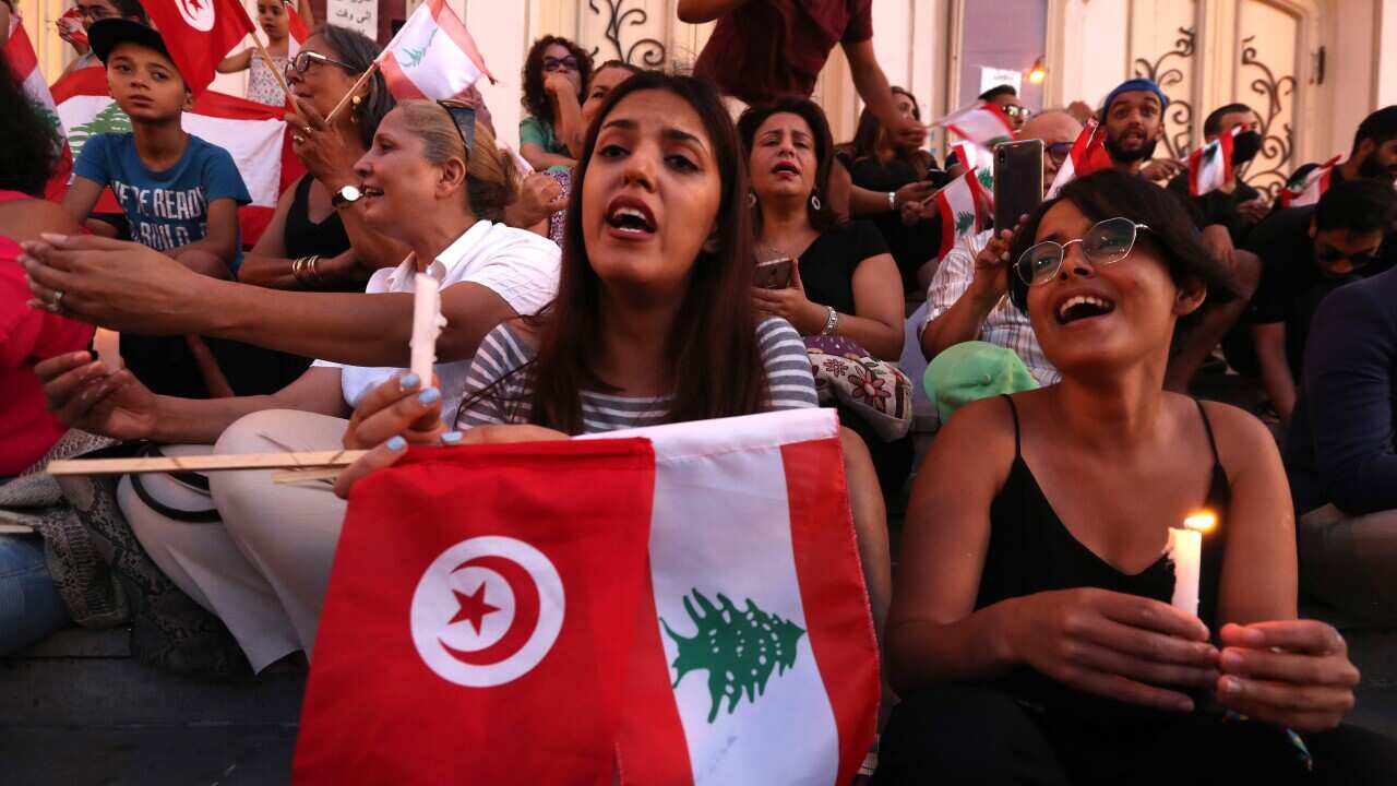 People hold Lebanese and Tunisian flags and candles during a solidarity vigil with the Lebanese people in Tunis.