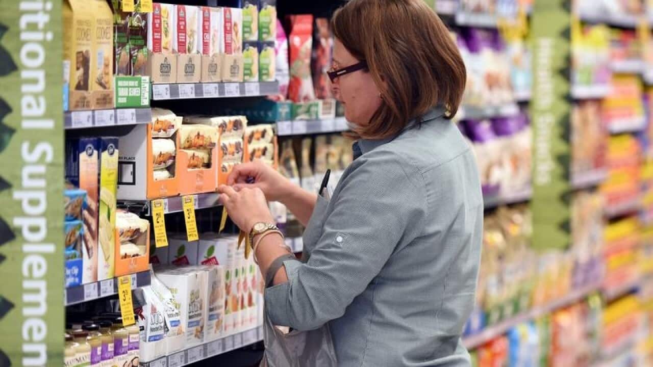 An employee puts price tags on selves at a Woolworths supermarket